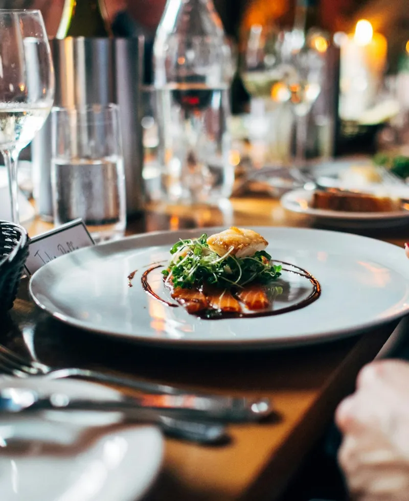 Atmosphärisches Stimmungsmotiv: ein sorgfältig angerichteter Teller im warmen Restaurantlicht